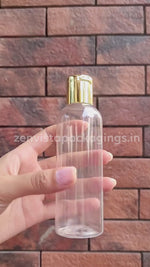 Load and play video in Gallery viewer, |ZMT73| TRANSPARENT PET BOTTLE WITH GOLD PLATED FLIPTOP CAP SILVER STREAK CAP Available Size: 100ml, 200ml
